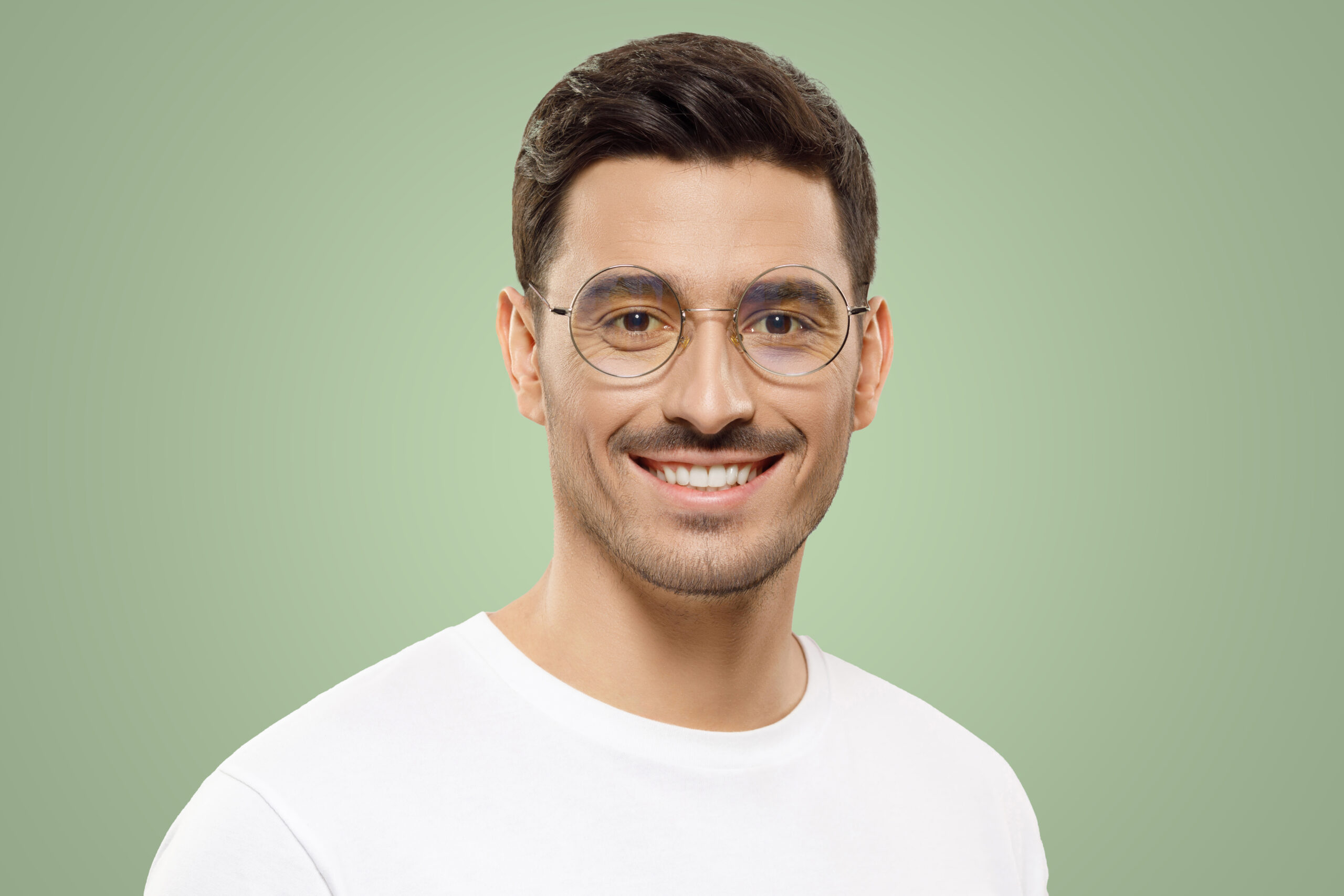 Image décorative d'un jeune homme souriant portant un t-shirt blanc et des lunettes rondes sur un fond vert.