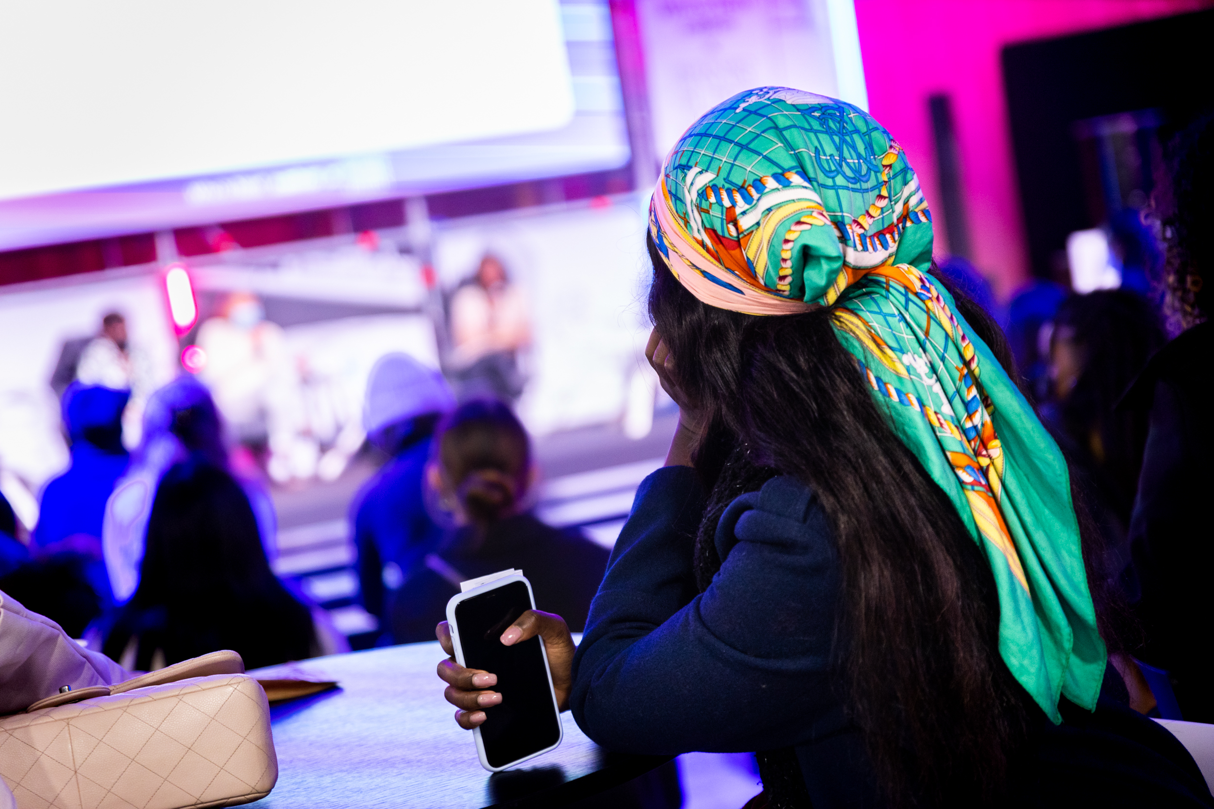 Image décorative d'une jeune femme avec un foulard vert écoutant une présentation.